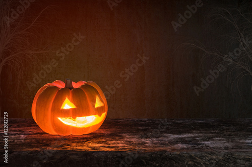 Happy halloween funny pumpkin Jack O'Lantern smiling face on grunge wood bokeh night dark background: Scary cute squash with candle light lit inside: Autumn holiday celebration festival decoration