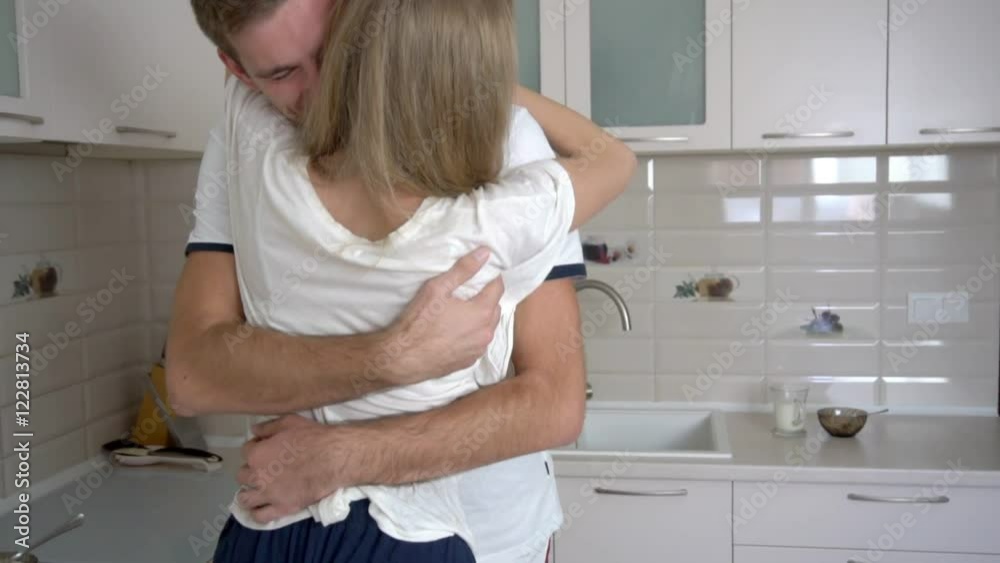 Young family couple hugging in the light kitchen slow motion Young family couple hugging in the light kitchen slow motion