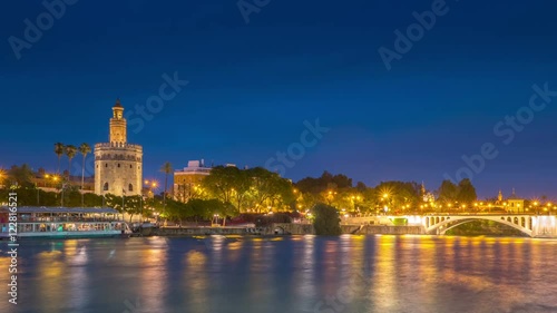 View of Golden Tower, Torre del Oro, of Seville, Andalusia, Spain over river Guadalquivir at sunset. Sunset timelapse with transition from day to night.