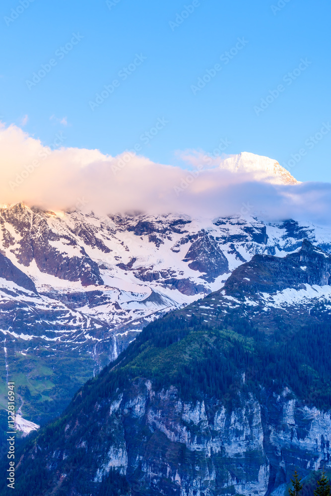 View of beautiful Alps with snow-capped mountain tops and nice clouds at sunset.