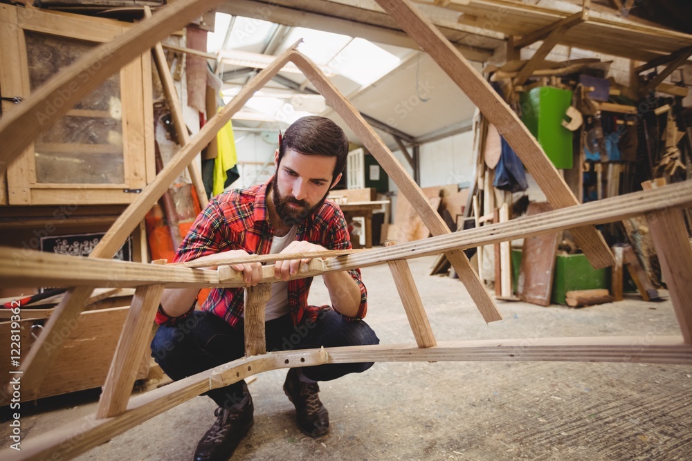 Carpenter preparing wooden boat frame in workshop Carpenter preparing wooden boat frame in workshop