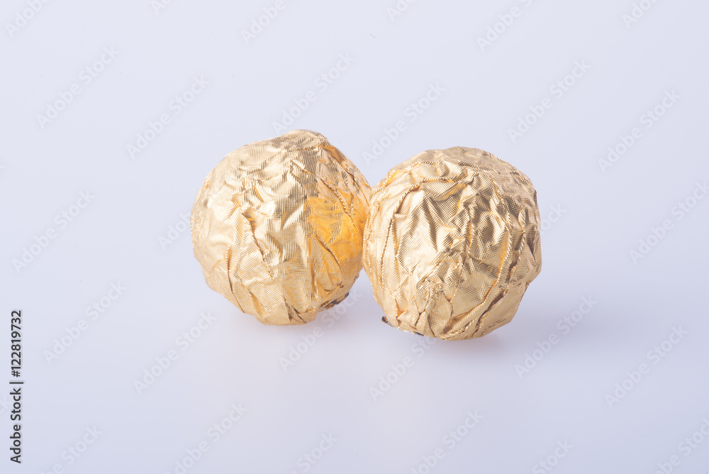 Fototapeta premium Chocolate ball in a gold foil paper on a background.