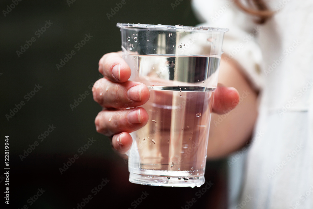 A glass of clean mineral water in woman's hands. Concept of environment protection, healthy lifestyle A glass of clean mineral water in woman's hands. Concept of environment protection, healthy lifestyle