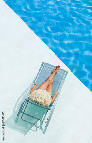 beautiful woman in a hat sitting on the edge of the pool