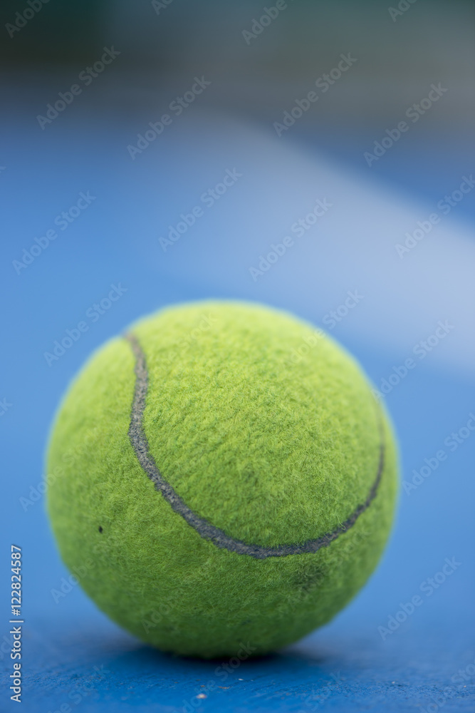 A Tennis ball and a racket at blue tennis court.