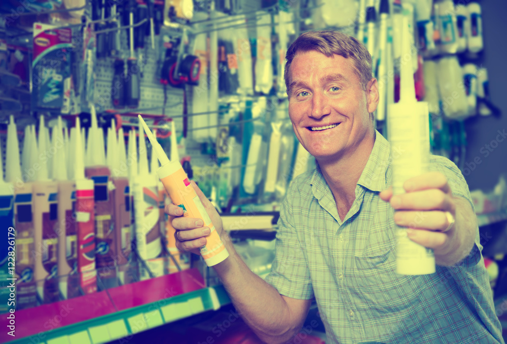 Wunschmotiv: mature man customer choosing sealant tube in hypermarket #122826179