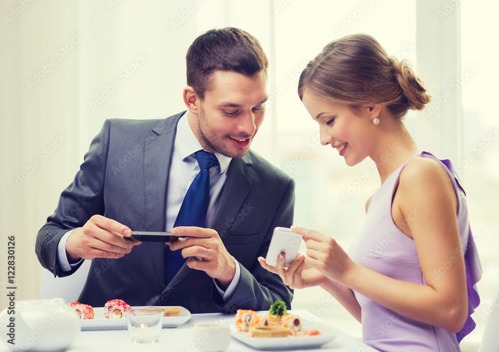 smiling couple with sushi and smartphones smiling couple with sushi and smartphones