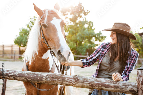 Konstfotografi Smiling woman cowgirl walking with horse on farm