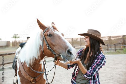 Cheerful woman cowgirl playing with horse in countryside © Drobot Dean