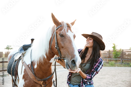 Happy woman cowgirl taking care of her horse