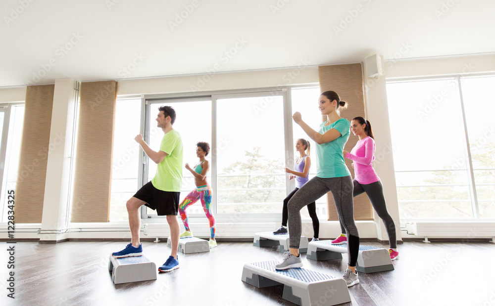 group of people exercising on steppers in gym group of people exercising on steppers in gym