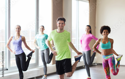 group of smiling people exercising in gym