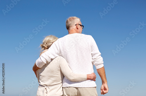 happy senior couple hugging on summer beach