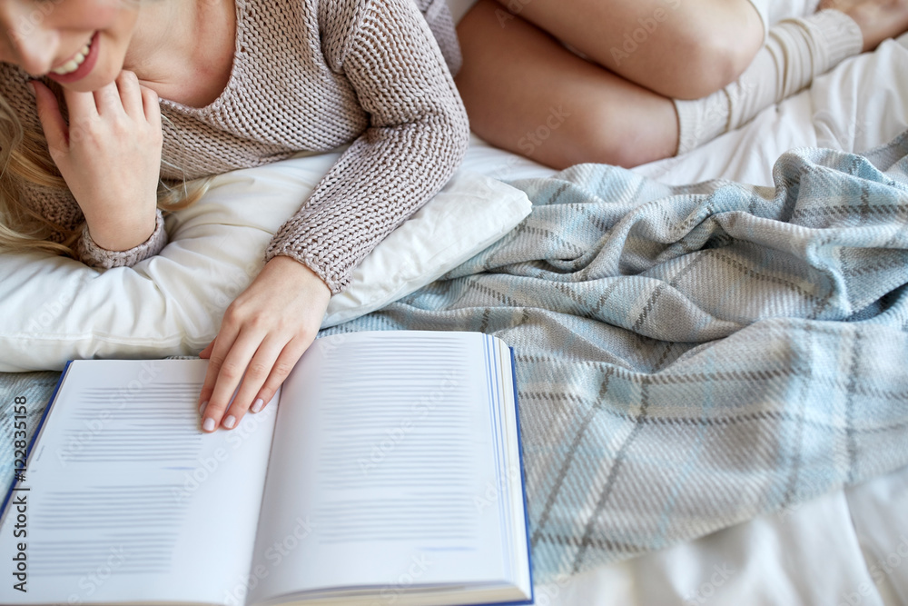close up of woman reading book in bed at home close up of woman reading book in bed at home