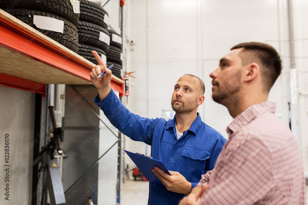 auto mechanic with clipboard and man at car shop