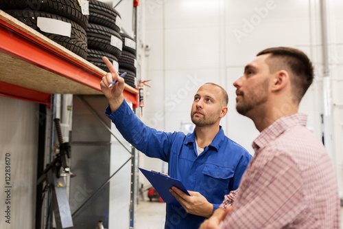 auto mechanic with clipboard and man at car shop