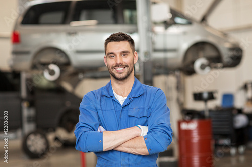 happy auto mechanic man or smith at car workshop