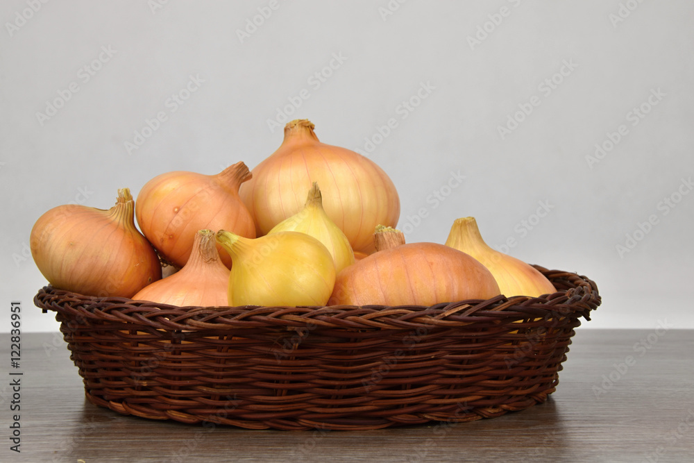 Onions in a wicker bowl. White background.