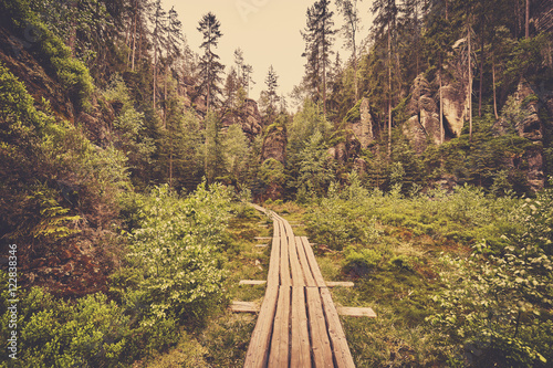 Retro toned photo of a wooden path in Adrspach Teplice rock town, Czech Republic.