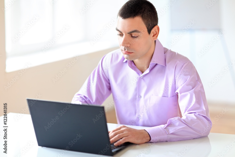 Portrait of young business man with laptop in the office Portrait of young business man with laptop in the office