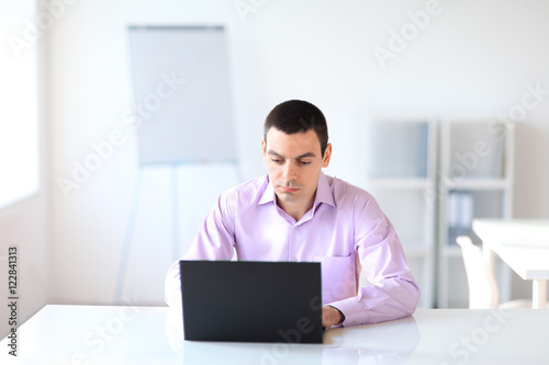 Portrait of young business man with laptop in the office