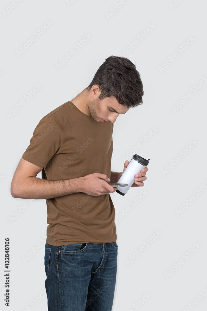 the young man stands with a thermocouple with coffee and phone the young man stands with a thermocouple with coffee and phone