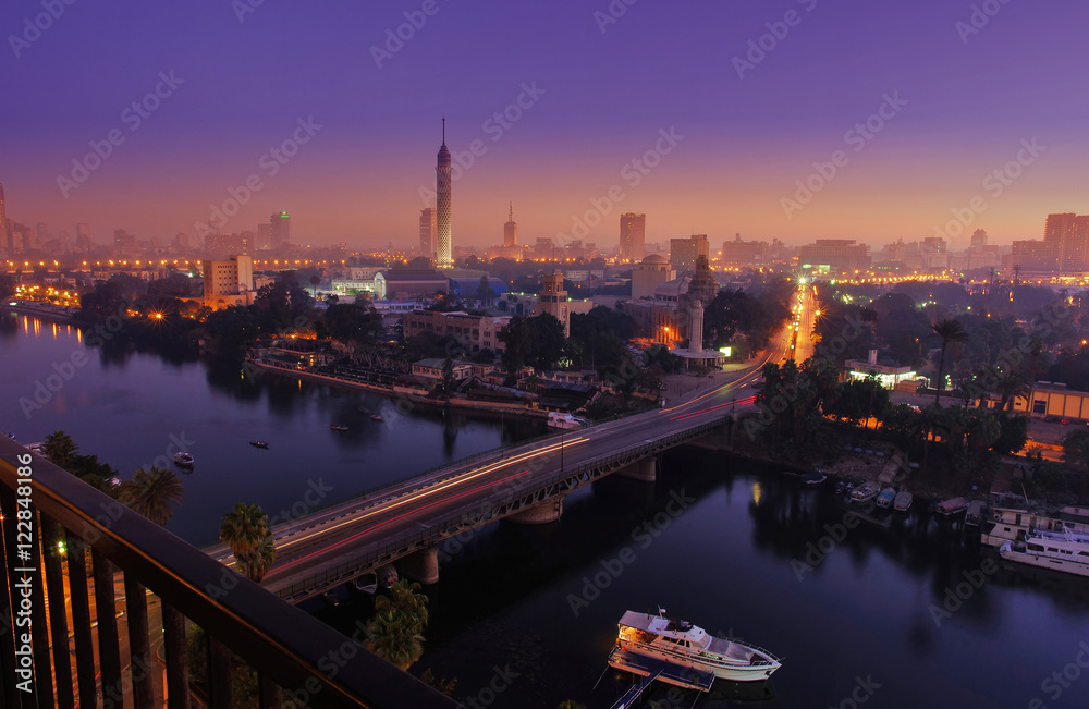 Fototapeta premium CAIRO - EGIPT - GRUDZIEŃ 2010: panorama Kairu i Nilu, ruch rano, wschód słońca, widok z góry, Wieża Kairska, budynki, auto i łodzie.