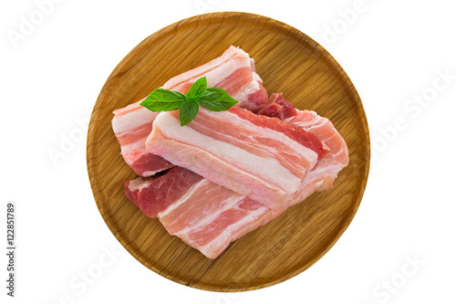 Slices of raw fresh pork belly cut on wooden plate isolated on white background