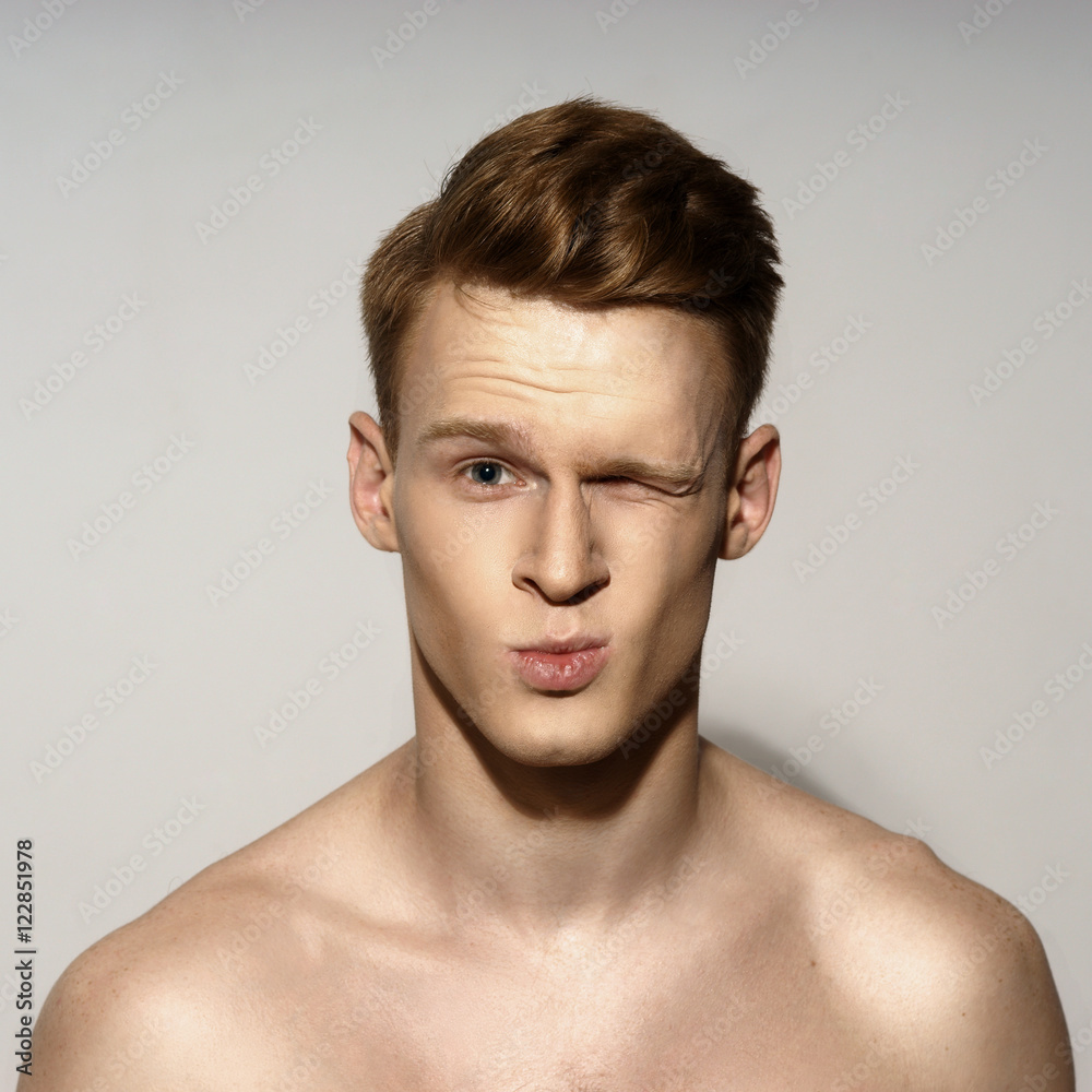 Obraz premium Studio fashion style closeup face portrait of young emotional man giving a kiss and winking