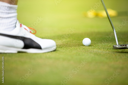 Golf ball and stick with golfer legs in background
