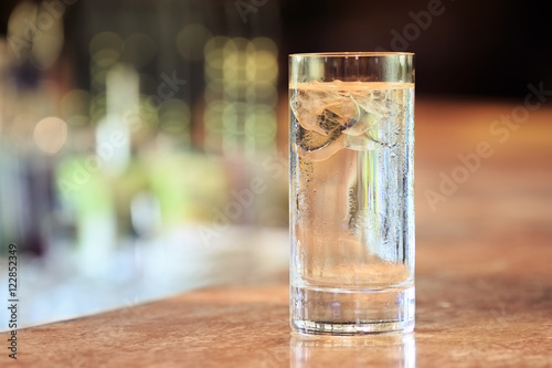 Glass of water with ice on the bar stand