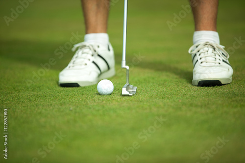 Golf ball and stick with golfer legs in background