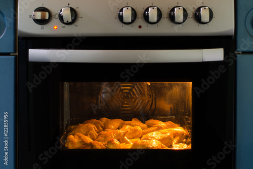 Chicken wings and potatoes baked in modern oven