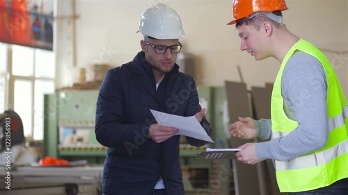 A carpenter have a serious conversation with supervisor in carpentry shop.