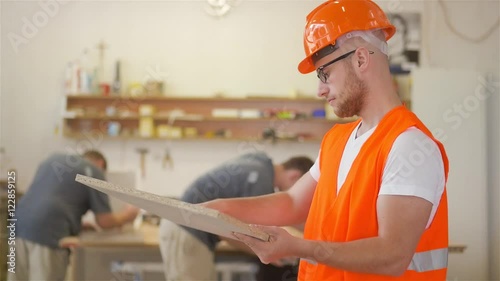 A carpenter is looking at the wooden desk in carpentry shop.