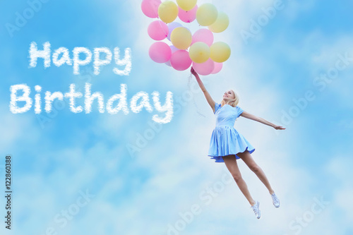Happy Birthday text and beautiful young woman with colorful balloons against blue sky