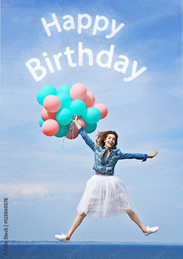 Happy Birthday text and beautiful young woman with colorful balloons against blue sky Happy Birthday text and beautiful young woman with colorful balloons against blue sky