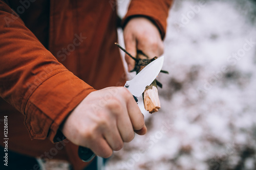 A man uses a knife to whittle a stick out hiking photo
