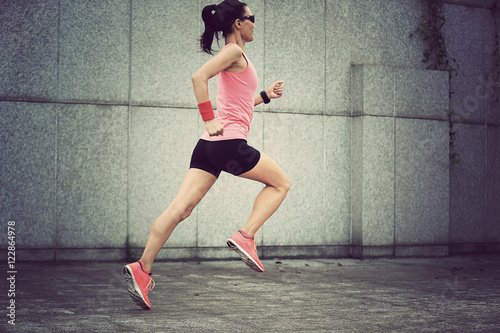 young fitness sport woman running against wall on city