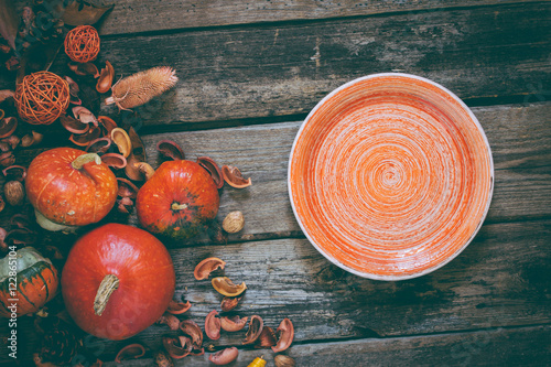 autumn decorated wooden table - pumpkins and orange ceramic plate. top view photo