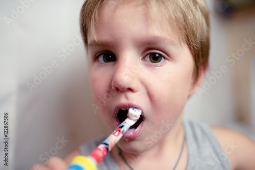 Little boy brushing teeth in bath with electric brush