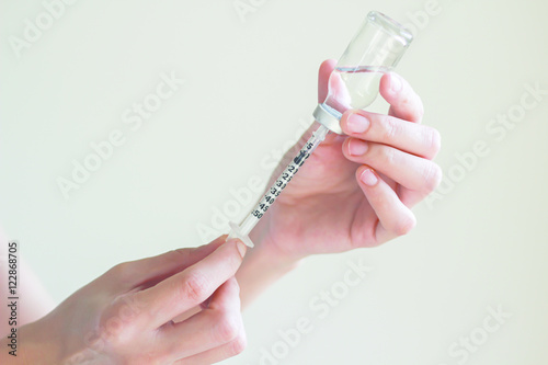 Nurse is  drawing  solution into syringe from vial for preparing