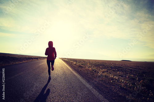 young fitness woman runner running on sunrise seaside trail..