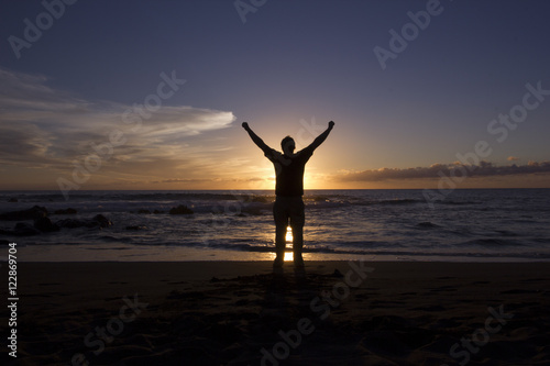 Mann mit ausgestreckten Armen am Strand Sonnenuntergang