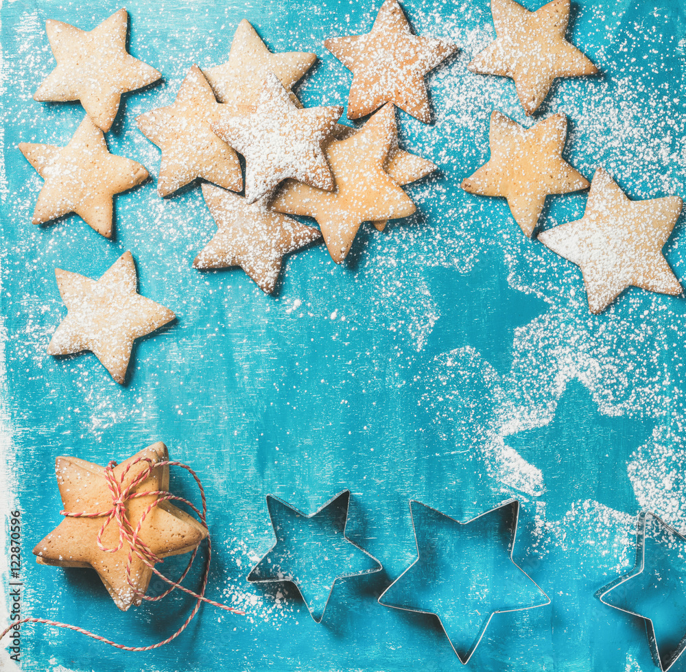 Christmas or New Year holiday food background. Sweet gingerbread cookies in shape of star sprinkled with sugar powder on blue painted plywood background, top view, copy space Christmas or New Year holiday food background. Sweet gingerbread cookies in shape of star sprinkled with sugar powder on blue painted plywood background, top view, copy space