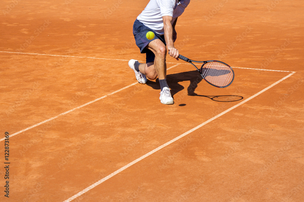 Male tennis player in action on the clay court on a sunny day Male tennis player in action on the clay court on a sunny day