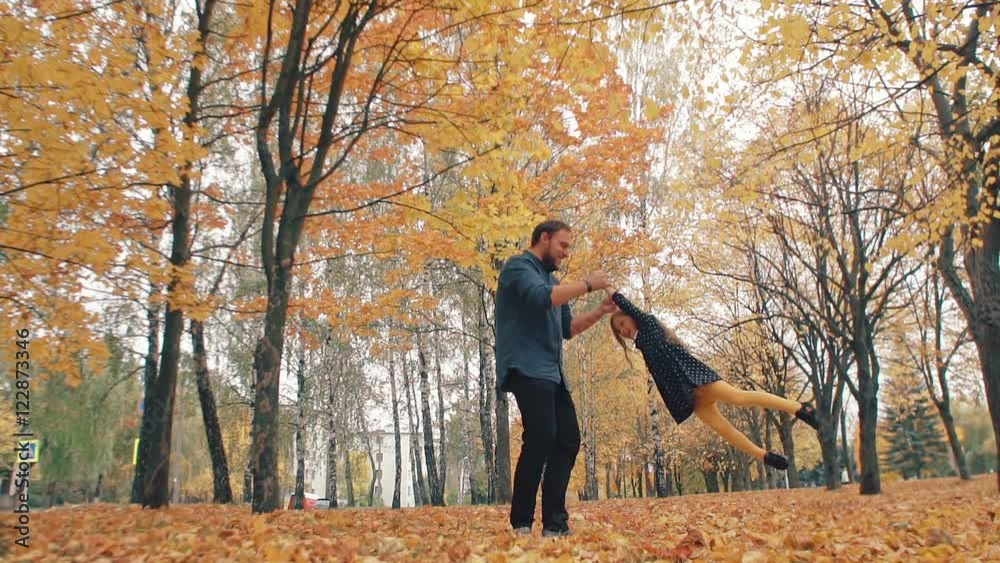 young handsome father turns his cute little daughter around holding her hand in autumn park slow mo young handsome father turns his cute little daughter around holding her hand in autumn park slow mo