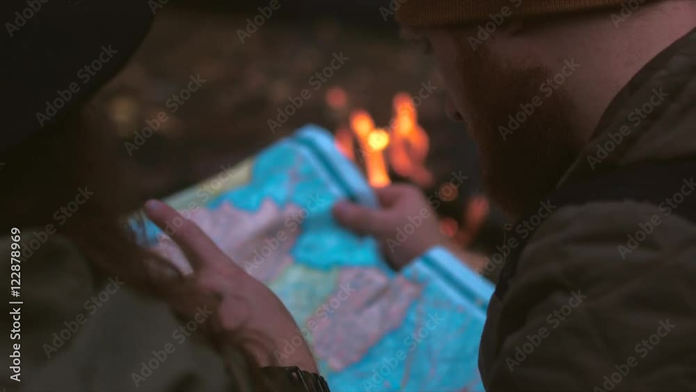 Hikers couple studying the map near bonfire. 4K UHD RAW edited footage Hikers couple studying the map near bonfire. 4K UHD RAW edited footage