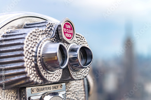 Beautiful view of downtown Manhattan from the Rockefeller Center. Binoculars with Empire State Building in the background.