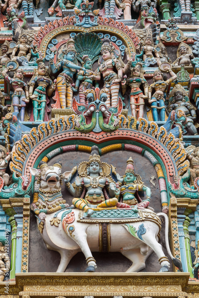Fototapeta premium Madurai, India - October 19, 2013: Closeup of double scene, the wedding of Shiva and Meenakshi, and both sitting on Nandi the bull. Facade of West Gopuram at Meenakshi Temple.